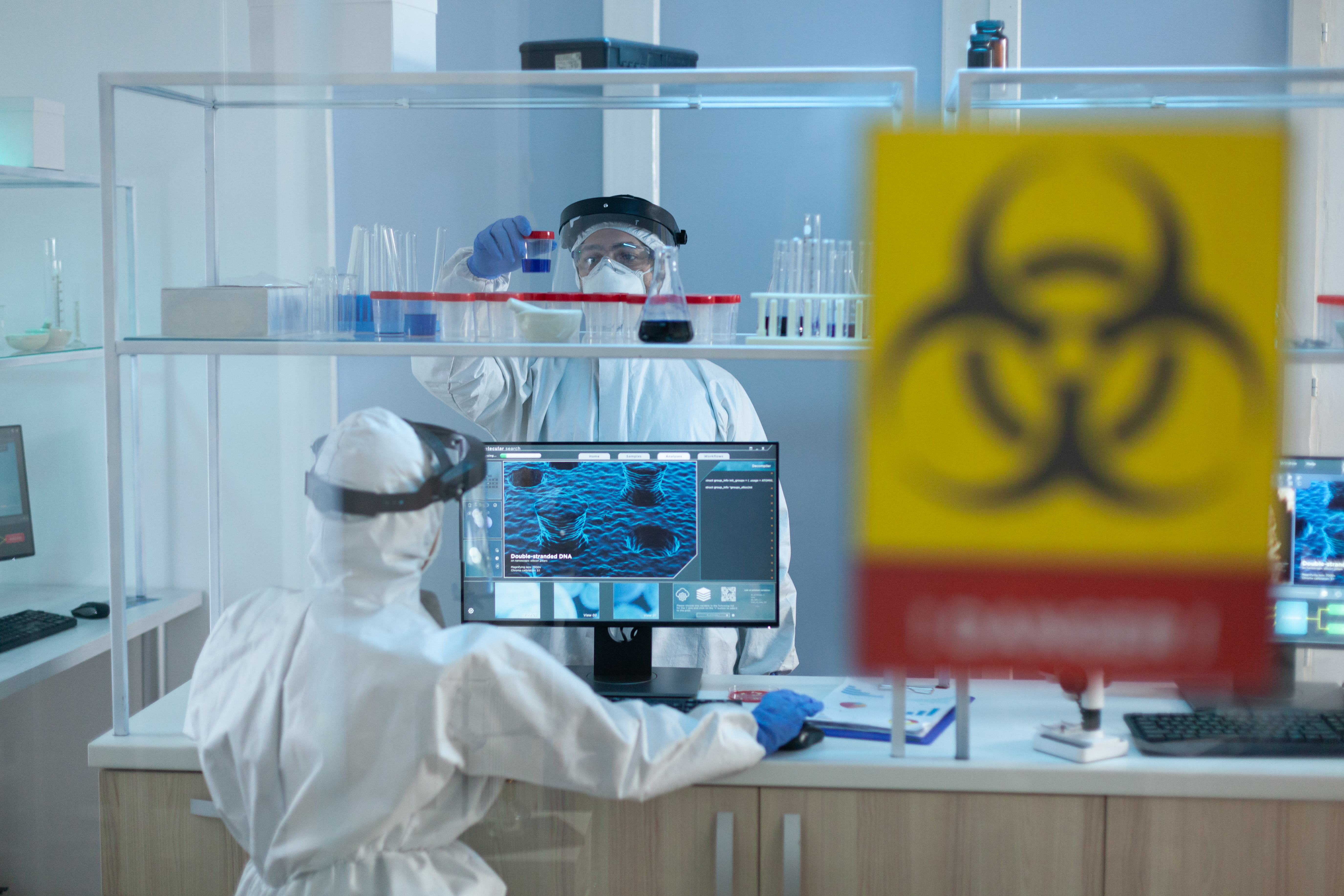 Deux scientifiques en combinaison stérile travaillant en salle blanche